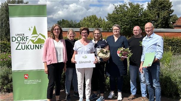 Machermentalität gewürdigt - Jetzt blickt Glinstedt in Richtung Landeswettbewerb Die Glinstedter Delegation freut sich über die Siegerurkunde, die von der Landesbeauftragten Karin Beckmann übergeben wurde.