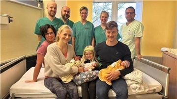 Die glückliche Familie mit ihren Drillingen, umgeben vom Team der Geburtshilfe, Kinderklinik und der Kinderintensivstation.