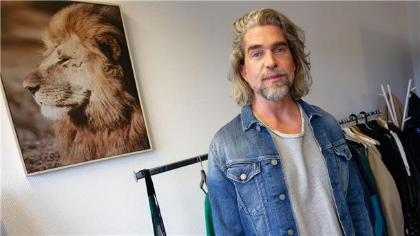 Die Haarpracht ist gar nicht mal so unterschiedlich: Nils Glagau vor dem Bild eines echten Löwens.