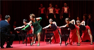 Revuetänzerinnen hinter Stühlen auf der Theaterbühne.