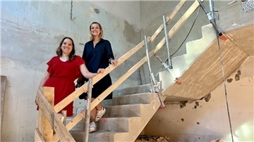 Zwei Frauen stehen im Rohbau auf einer Treppe