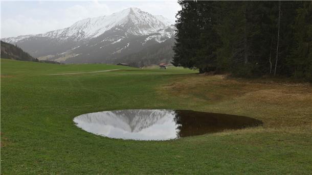Saharastaub über Deutschland zieht ab Die im Dunst liegenden Alpen spiegeln sich in einem Weiher. Der Saharastaub-Höhepunkt ist überschritten.
