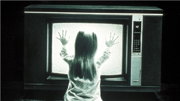 Die kleine Carol Anne (Heather O’Rourke) spricht mit dem Fernseher - eine Szene des Films „Poltergeist“.