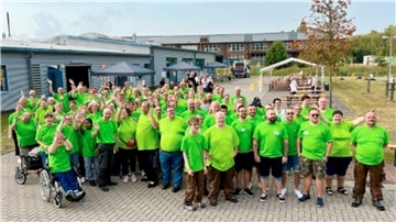 Gruppe in grünen T-Shirts auf einem Hof.