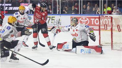 Ein Kölner Eishockeyspieler fälscht eine Scheibe vor dem Bremerhavener Tor ab.