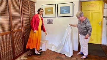 Zwei Frauen enthüllen Bilder in Ausstellung