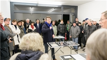 Die Kunst an den Wänden - die Computer-Ausdrucke - sind bei der Eröffnung nicht zu sehen. Viele Besucher drängeln sich im Kabinett für aktuelle Kunst, um zusammen mit Moritz Wesseler (Mitte, mit blauem Schal) auf Zeitreise zu gehen.