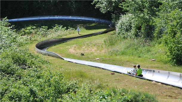Zwei Kinder auf einer Sommerrodelbahn.