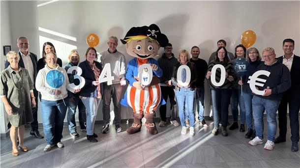 Elbe-Weser-Dreieck: Volksbank stärkt Schulen zum Weltspartag Viele Männer und Frauen stehen nebeneinander und einige halten große Zahlen in der Hand.