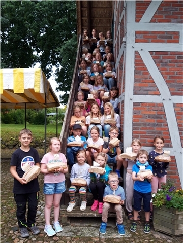 Kinder mit selbst gebackenem Brot an einem Heimathaus