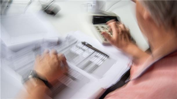 Bremerhaven: Immer mehr Kritik an Plänen für Magistratsreform Ein Mann sitzt vor einem Blatt Papier und einem Taschenrechner.