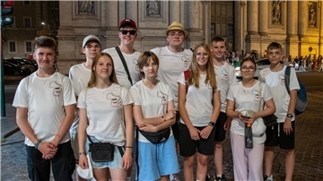 Eine Gruppe von zehn jungen Menschen in einheitlichen weißen T-Shirts steht nebeneinander.