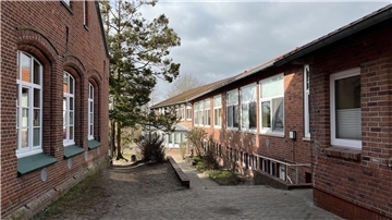 Die Midlumer Grundschule besteht schon jetzt aus mehreren Gebäudeteilen. Ab Frühjahr 2025 soll der jüngste Komplex (rechts) um ein weiteres Gebäude für die Mensa ergänzt werden.