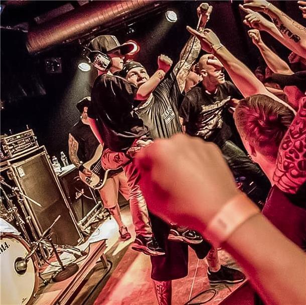 Als Kind auf der Metal-Bühne: Jamey Hubel begeistert Musiker und Fans Ein Mann auf einer Bühne hat einen kleinen Jungen auf dem Arm.
