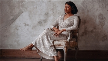 Vollmond-Lounge im Pferdestall: Malia präsentiert Neo Soul-Jazz Eine dunkelhäutige Frau in einem schimmernden Kleid sitzt auf einem Stuhl.