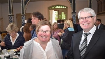 Eine Frau und ein Mann stehen nebeneinander, dahinter sind ganz viele Menschen zu sehen.