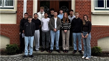 Auszubildende in verschiedenen Berufen stehen für ein Gruppenfoto vor einem Haus.