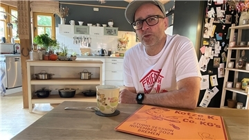 Ein Mann mit Brille und Mütze sitzt an einem Tisch, vor ihm ein Becher Tee und eine Schallplatte. Es handelt sich um den Nordenhamer Stephan Beckmann.