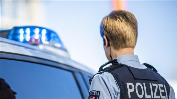 Bedrohung und häusliche Gewalt: Polizei schnappt Trio in Dorum Eine Polizistin steht vor einem Streifenwagen, dessen Blaulicht leuchtet.