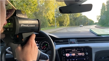 Mann im Auto hält sich ein Messgerät vor die Augen