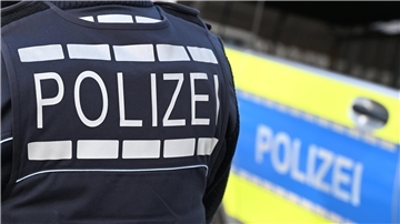 Ein Polizist steht an einem Polizeiwagen.