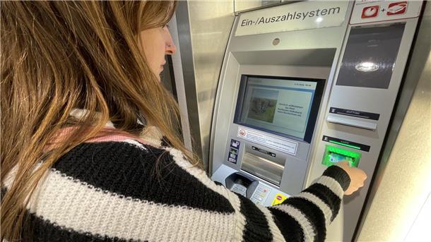 Eine Frau hebt mit ihrer Karte Geld am Geldautomaten ab. 