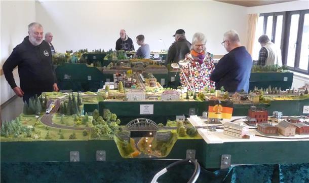 Leute betrachten eine riesige Modelleisenbahnanlage