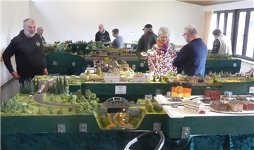 Leute betrachten eine riesige Modelleisenbahnanlage