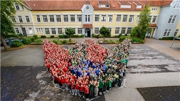 Eine große Gruppe Schüler steht auf einem Schulhof.