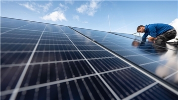 Mitarbeiter montieren Photovoltaikmodule auf dem Dach eines Wohnhauses. 