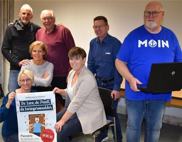 Drei Frauen und vier Männer bei einem Gruppenfoto. Zwei von ihnen halten ein Theaterplakat.