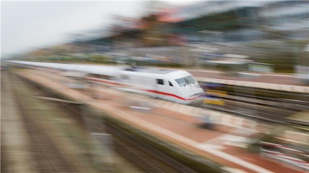 Ein weißer Zug rast durch einen Bahnhof.