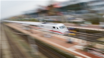 Ein weißer Zug rast durch einen Bahnhof.
