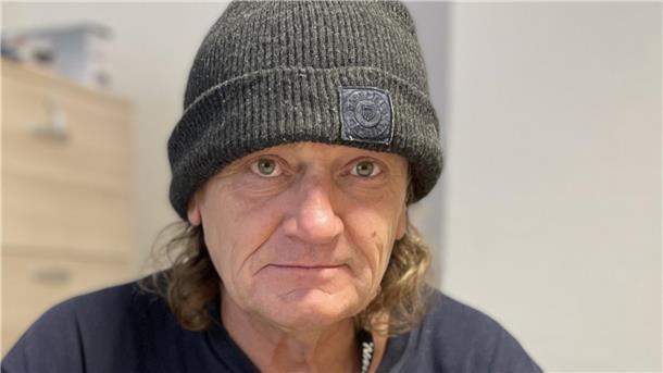 Mann mit Mütze und schulterlangen Haaren.