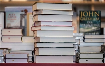  Ein Bücherstapel liegt in einer Buchhandlung auf einem Verkaufstisch. Die Stadtbibliothek Cuxhaven lädt am 4. April zur „Nacht der Bibliotheken“ ein und bietet ein Programm mit Musik, Impro-Theater und einem Quiz-Abend.