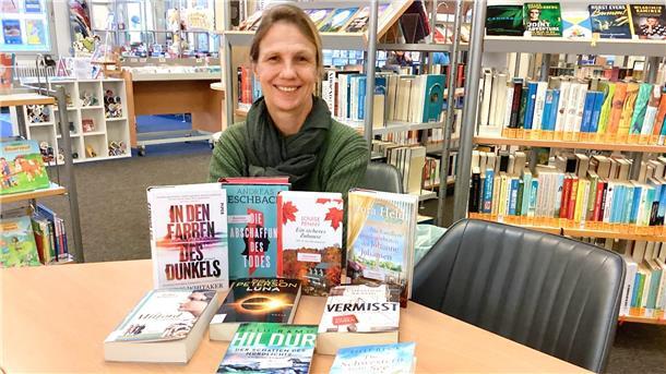 Schluss mit Langeweile: Diese Veranstaltungen plant die Stadtbücherei Nordenham Eine Frau sitzt in der Stadtbücherei Nordenham an einem Tisch und präsentiert dort einige Bücher.