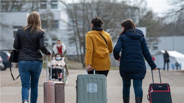 Frauen ziehen Koffer hinter sich her