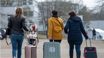 Frauen ziehen Koffer hinter sich her