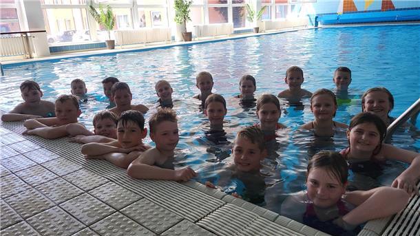 Deshalb kann in Burhave endlich wieder das Schulschwimmen stattfinden Dutzende Kinder stehen am Beckenrand eines Schwimmbeckens und lächeln in die Kamera.