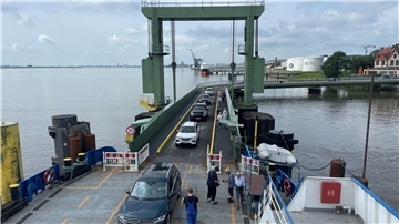 Autos fahren über eine Brücke auf eine Fähre.