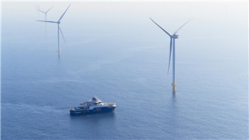 Ein Schiff liegt in einem Offshore-Windpark vor Anker. 