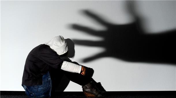 Gruppenvergewaltigungen in Bremerhaven: Was ist dran am Migrations-Zusammenhang? Schatten einer Hand über sitzender Frau.