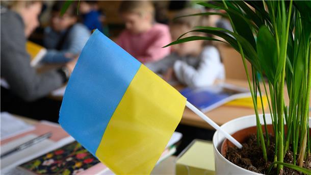 Einwohnerstatistik zeigt: Nordenham ist eine bunte Stadt mit 91 Nationen In einem Blumentopf steckt eine ukrainische Flagge, dahinter sind Menschen an Tischen zu sehen.