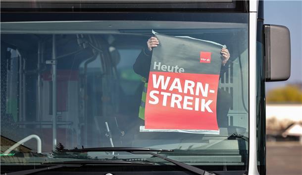 Warnstreik der KVG: Eingeschränkter Busverkehr im Landkreis Cuxhaven Mensch klebt ein weiß-rotes Plakat an die Windschutzscheibe eines Busses.