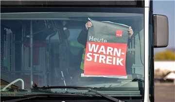 Warnstreik der KVG: Eingeschränkter Busverkehr im Landkreis Cuxhaven Mensch klebt ein weiß-rotes Plakat an die Windschutzscheibe eines Busses.