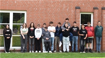Eine Gruppe Schüler steht vor einem Gebäude.