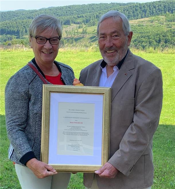 Eine ältere Frau und ein älterer Mann halten eine Dankurkunde in der Hand.  