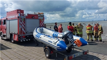 Bild mit einem Feuerwehrauto, einem Schlauchboot und Einsatzkräften von Feuerwehr und DLRG am Watt vor dem Friesenstrand Tossens.