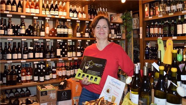 Dominique Wempe steht vor ihren Weinregalen. In den Händen hält sie ein Oenaromset. 