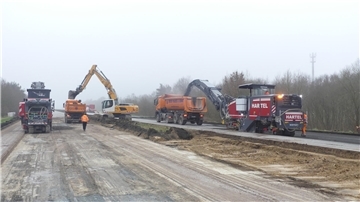 Zwei Asphaltfräsen auf der A27. Zwei LKWs sind mit auf dem Bild. 